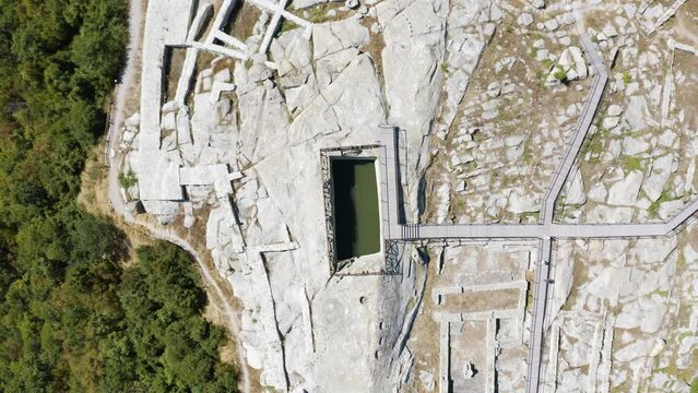 Overhead drone shot of a water reservoir situated in the middle of the complex of the historical landmark of Perperikon, in the province of Kardzhali in Bulgaria.