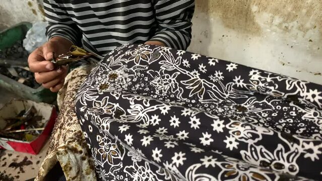 Indonesian old women's hand making batik clothes. Batik is an Indonesian technique of wax-resist dyeing applied to the whole cloth.