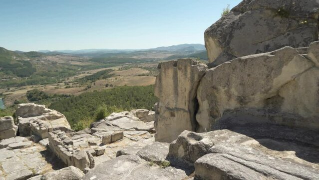 Panning from  the left to the right side of the frame, showing the rock structures of the ancient city of Perperikon and the valley below in the province of Kardzhali in Bulgaria.