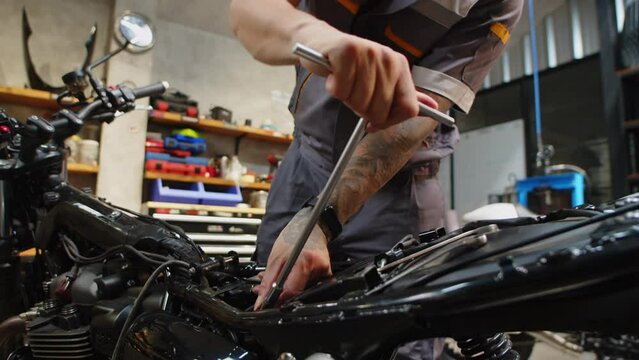 Cropped shot of unrecognizable mechanic using valve adjusting wrench for motorbike engine repairing