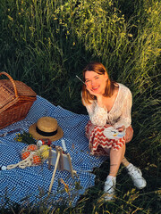 Painting memories: young woman captures sunset on a blue blanket at picnic