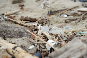 Déchets plastiques et divers objets sur le sable en bord de plage. Détritus sur la plage. 