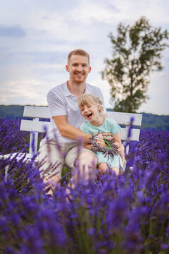father and daughter are sitting on a bench in a lavender field