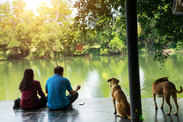 Lover to sit on the terrace near the riverside with dogs and sunlight background. Tourist to relax and so happy on holiday.