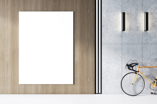 An office interior featuring a blank white poster frame on a wall, a modern bicycle on a gray concrete floor, and elegant wall lighting, concept of mockup space. 3D Rendering