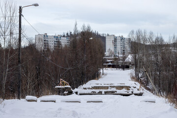 View of a snow-covered road and a collapsed bridge. Damaged bridge. The bridge collapsed as a result of summer floods in 2022. Consequences of an emergency. Tynda, Amur region, Russia - Jan 22, 2024.