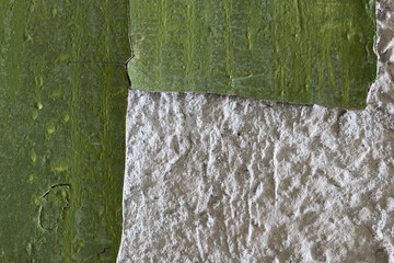 Green peeling paint on the wall. Old concrete wall with cracked flaking paint. Weathered rough painted surface with patterns of cracks and peeling. High resolution texture for background and design.