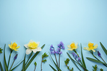 Beautiful bouquet of fresh daffodils and small flowers on a blue background. Simple holiday spring greeting card, invitation card. Top view, flat lay. Space for text. Floral banner. - obrazy, fototapety, plakaty