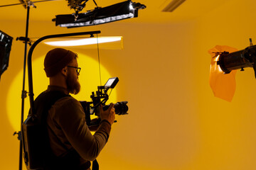 Videographer capturing footage in a yellow room with a camera