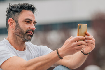 portrait of attractive man with beard outdoors looking at mobile phone