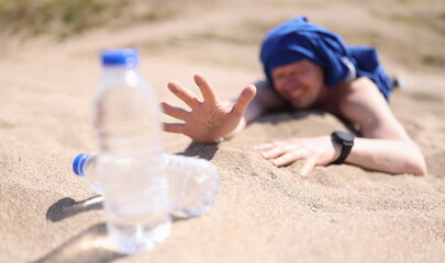 Dehydrated man crawling on sand for bottle of drinking water closeup. Better to quench your thirst...