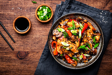 Stir fry turkey slices with red paprika, mushrooms, chives and sesame seeds with ginger, garlic and soy sauce. Old wooden table background, top view