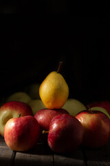 Red apples and yellow pear on a wooden table