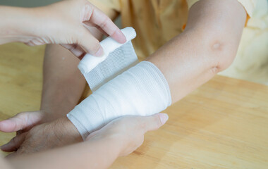 Daughter wraps bandage around mom's wrist in the event of a sprain or accident at home.