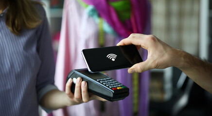Female hand in dress market hold modern POS terminal closeup background. Man paying with snarthpone help program. Hack bunking system concept