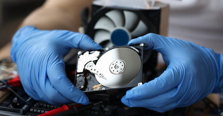 Hdd pc repair service concept. Male hand in blue protective gloves hold silver hdd and install pc...