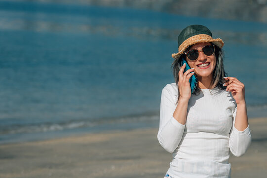 young woman talking on mobile phone on the beach