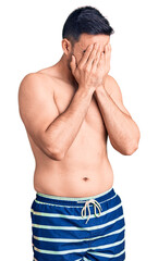 Fototapeta premium Young handsome man wearing swimwear with sad expression covering face with hands while crying. depression concept.