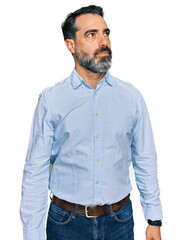 Middle aged man with beard wearing business shirt smiling looking to the side and staring away...