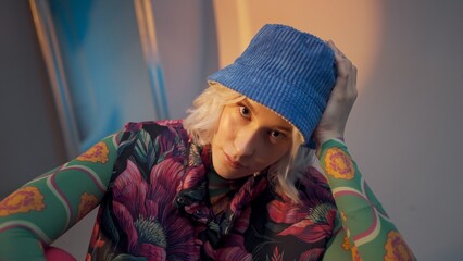 Cool hipster student woman wearing stylish outfit looking at camera and correcting her hat