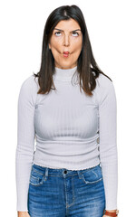 Beautiful brunette woman wearing casual clothes making fish face with lips, crazy and comical gesture. funny expression.