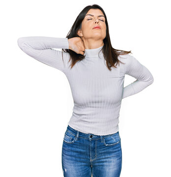 Beautiful brunette woman wearing casual clothes suffering of neck ache injury, touching neck with hand, muscular pain