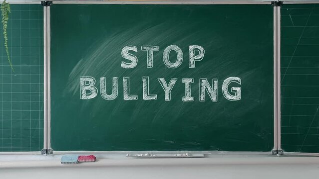 STOP BULLYING is written in chalk on a green chalkboard. Social problems of humanity. Stop school bullying