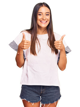 Young hispanic woman wearing casual clothes success sign doing positive gesture with hand, thumbs up smiling and happy. cheerful expression and winner gesture.