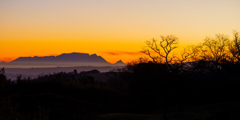 Fototapeta premium Silhouette of Table Mountain against a dusk sunset sky in Cape Town