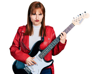 Obraz premium Redhead young woman playing electric guitar skeptic and nervous, frowning upset because of problem. negative person.