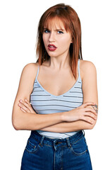 Redhead young woman with arms crossed gesture clueless and confused expression. doubt concept.