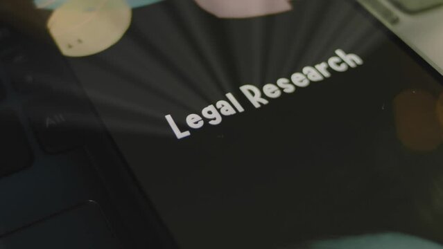 Legal Research inscription on smartphone screen. Graphic presentation on black background with bokeh lights. Light rays. Legal concept