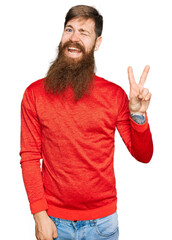 Redhead man with long beard wearing casual clothes smiling with happy face winking at the camera...