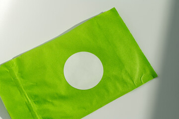 Round white sticker on green poly mailer envelope.