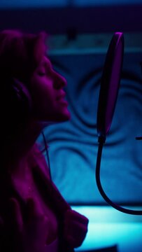Female singer gesturing hands and singing song in neon light studio