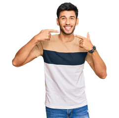Young handsome man wearing casual clothes smiling cheerful showing and pointing with fingers teeth and mouth. dental health concept.