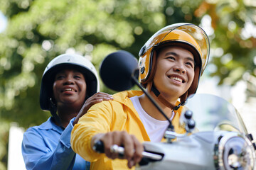 Smiling motorbike taxi driver and passenger riding in city