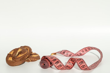 Chocolate marble cookie slices with pink measuring tape on white background.