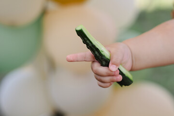 Child holds cucumber and points with his finger
