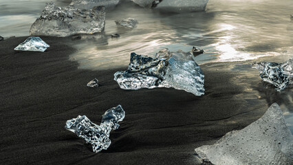 Am Diamond Beach in Island liegen Eisbrocken wie Diamanten im schwarzen Sand, Aufnahme eines Einzelnen Eisbrocken - obrazy, fototapety, plakaty