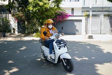 Young Vietnamese man working as courier riding motorbike