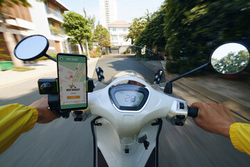 POV of motorbike taxi driver riding fast and checking requests on smartphone