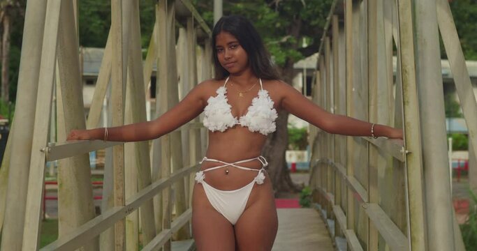 An Indian girl, adorned in a white bikini, enjoys the tranquility of a Caribbean beach with its soft white sand on a bridge