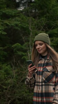 Portrait of young hiker woman using mobile phone navigation or social media app