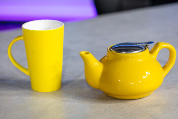 Yellow ceramic teapot and cup on the table in cafe