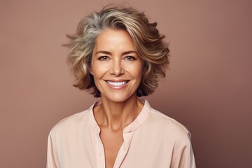 A woman with a short, gray hair is smiling and wearing a pink shirt - Powered by Adobe