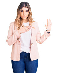 Young caucasian woman wearing business clothes swearing with hand on chest and open palm, making a...