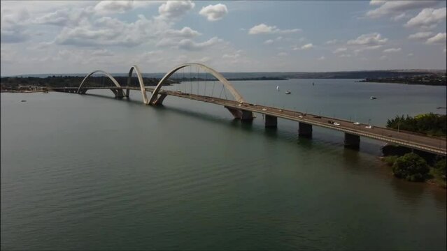 Drone shot of a beautiful bridge located over a wide river, with cars passing by.