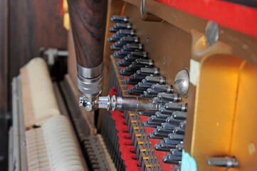 Tuner inside of a piano with little hammer