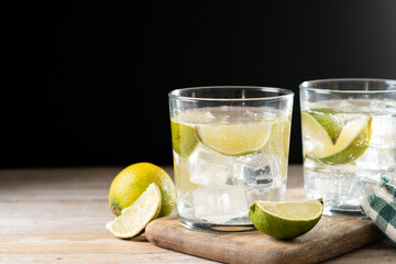 Glass of vodka tonic cocktail on wooden table. Copy space